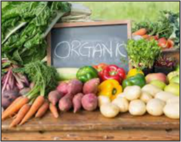 A colorful assortment of fresh vegetables including carrots, bell peppers, and potatoes on a rustic wooden table, featuring a small chalkboard sign in the center reading "ORGANIC".